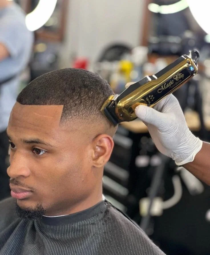 Barber creating a fade haircut with gold clippers, supplied by NBD