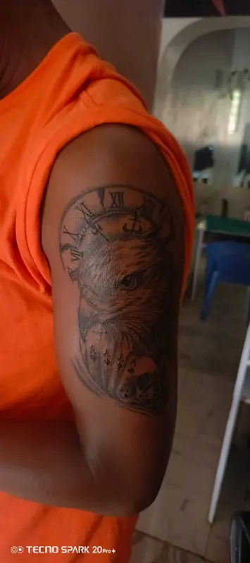 Shaded eagle and clock tattoo on an upper arm, supplied by NBD