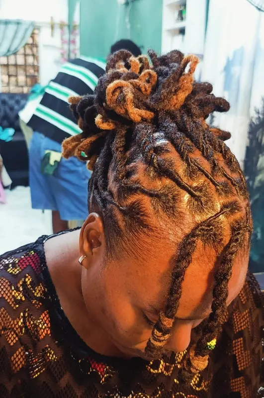 Loc updo with warm golden tips and patterned sectioning, supplied by NBD