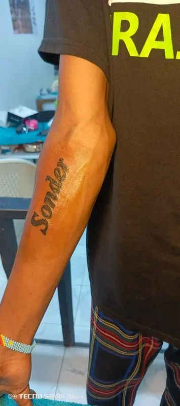 Cursive lettering tattoo along the forearm, supplied by NBD